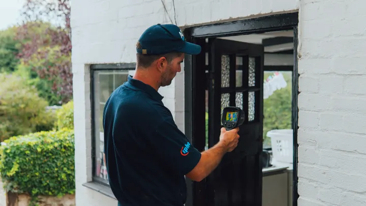 An ADI engineer examining a painted brick wall with a thermal imaging camera